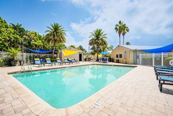 A large outdoor swimming pool surrounded by palm trees and lounge chairs